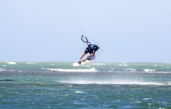 Dynamic kitesurfing action over ocean waves in Adicora, capturing the thrill of summer water sports.