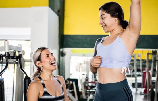 Two women in activewear sharing a joyful moment during a gym workout session.